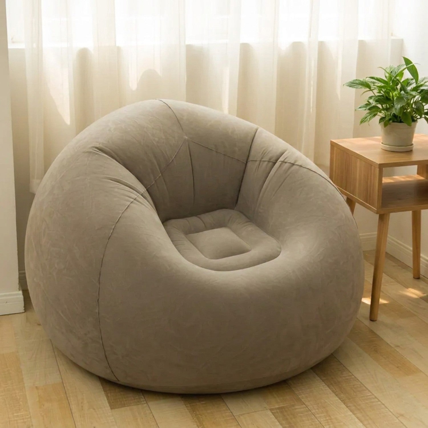 Fauteuil gonflable pouf géant gris installé dans un salon lumineux près d'une table d'appoint