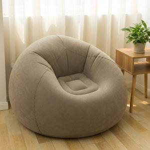 Fauteuil gonflable pouf géant gris installé dans un salon lumineux près d'une table d'appoint
