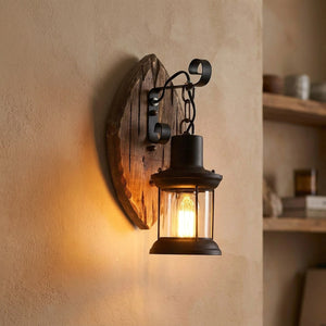 Applique murale industrielle avec cage en métal noir et support en bois arrondi éclairée d'une lumière chaude