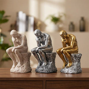 Statue Le Penseur de Rodin en finition beige argentée et dorée sur une console en bois