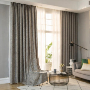 Rideau chenille gris à motif géométrique doré suspendu dans un salon lumineux