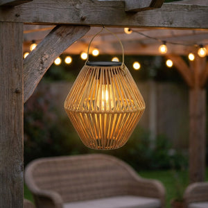 Lanterne solaire en bambou tressé forme diamant suspendue à une poutre de pergola le soir