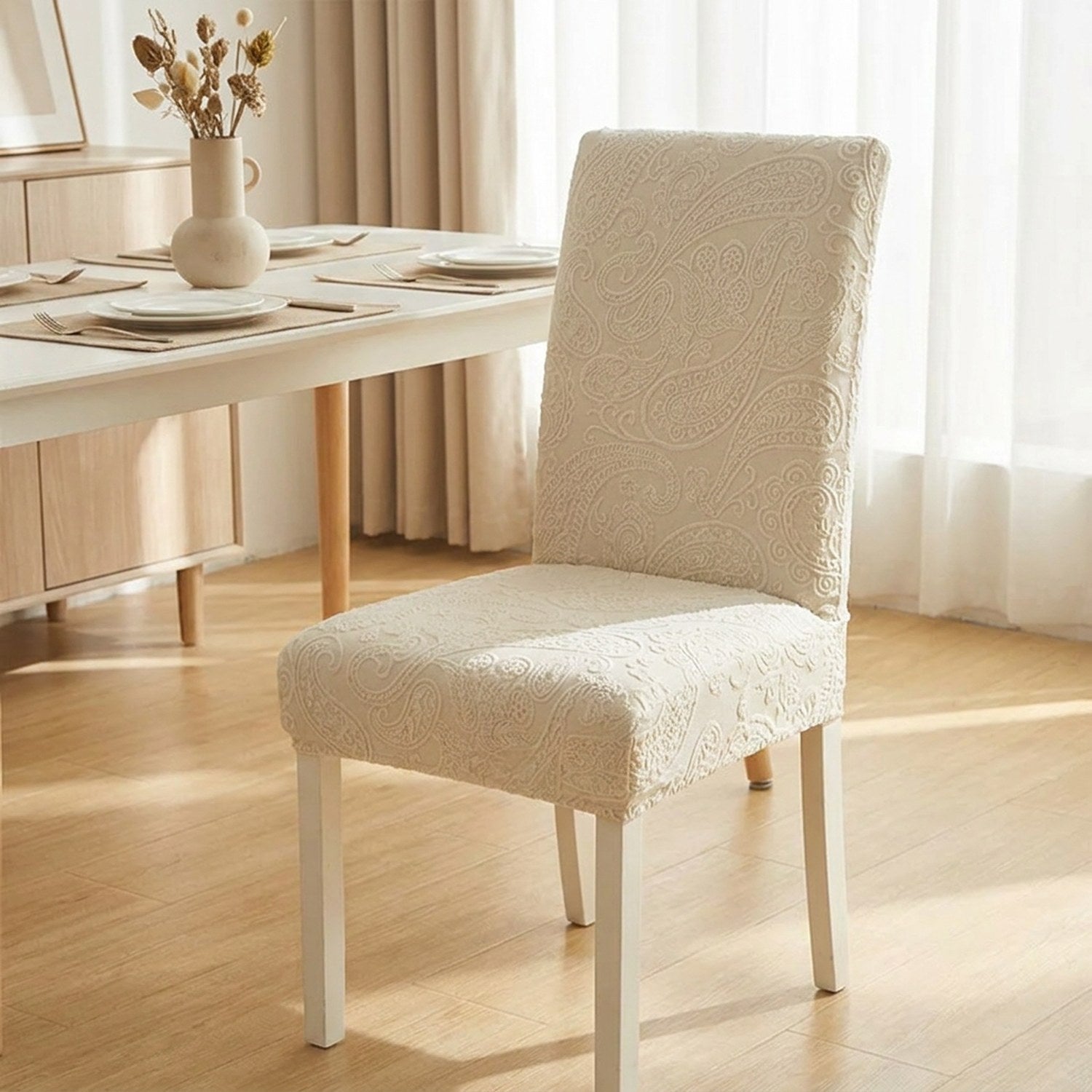 Housse de chaise extensible en jacquard relief beige installée sur une chaise de salle à manger claire