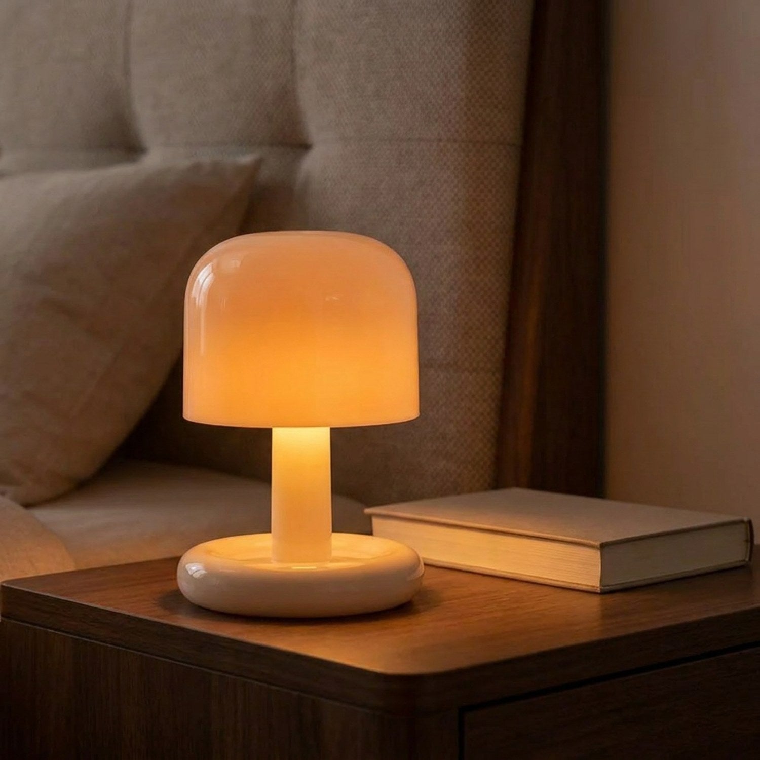 Lampe champignon beige allumée diffusant une lumière chaude posée sur une table de chevet en bois