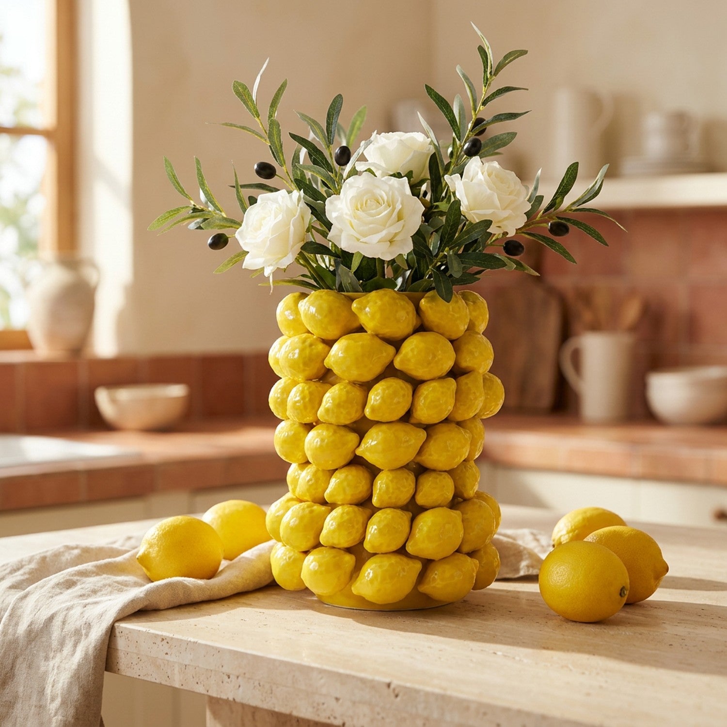 Vase citron en céramique jaune couvert de citrons en relief garni de roses blanches sur un plan de travail en travertin