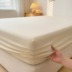 Drap housse en coton doux de couleur unie installé sur un lit fait dans une chambre lumineuse