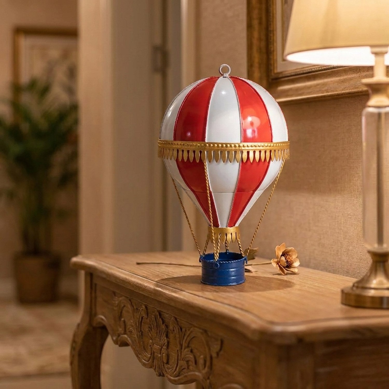 Ballon à air chaud en métal forgé bordeaux doré posé sur une console en bois dans un intérieur chaleureux