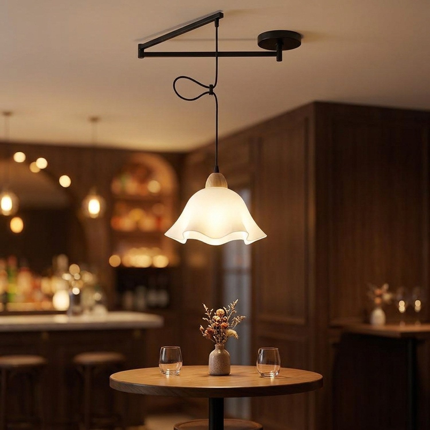 Lampe suspendue design à bras orientable noir, abat-jour fleur, au-dessus d'une table de bar