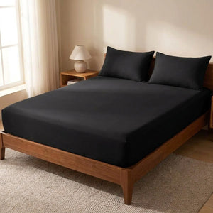 Drap housse noir ajusté sur un lit fait dans une chambre lumineuse et épurée
