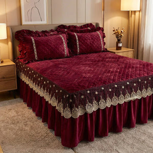 Couvre-lit matelassé en velours grenat avec jupe à volants en dentelle installé sur un lit dans une chambre chaleureuse