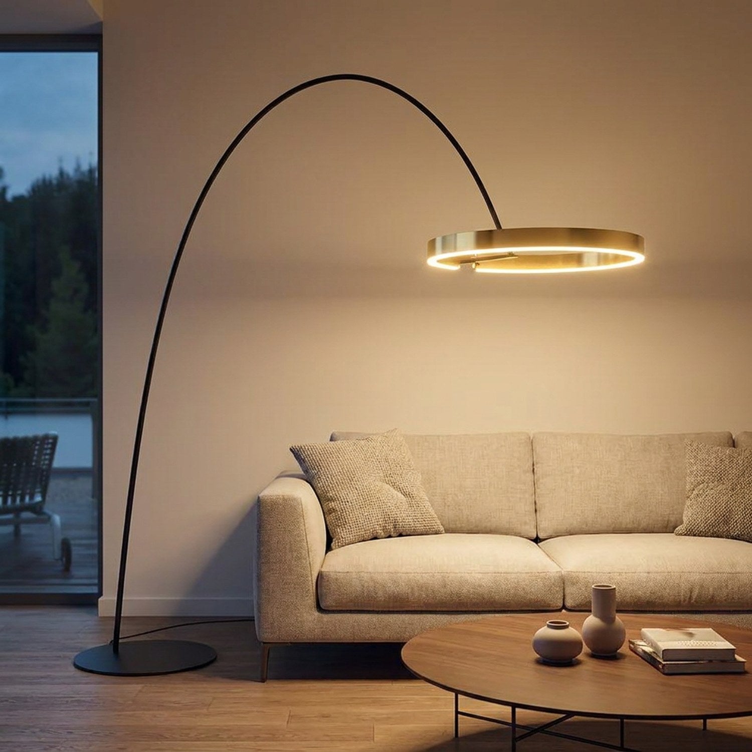 Lampadaire arc italien anneau LED doré allumé au-dessus d'un canapé dans un salon chaleureux