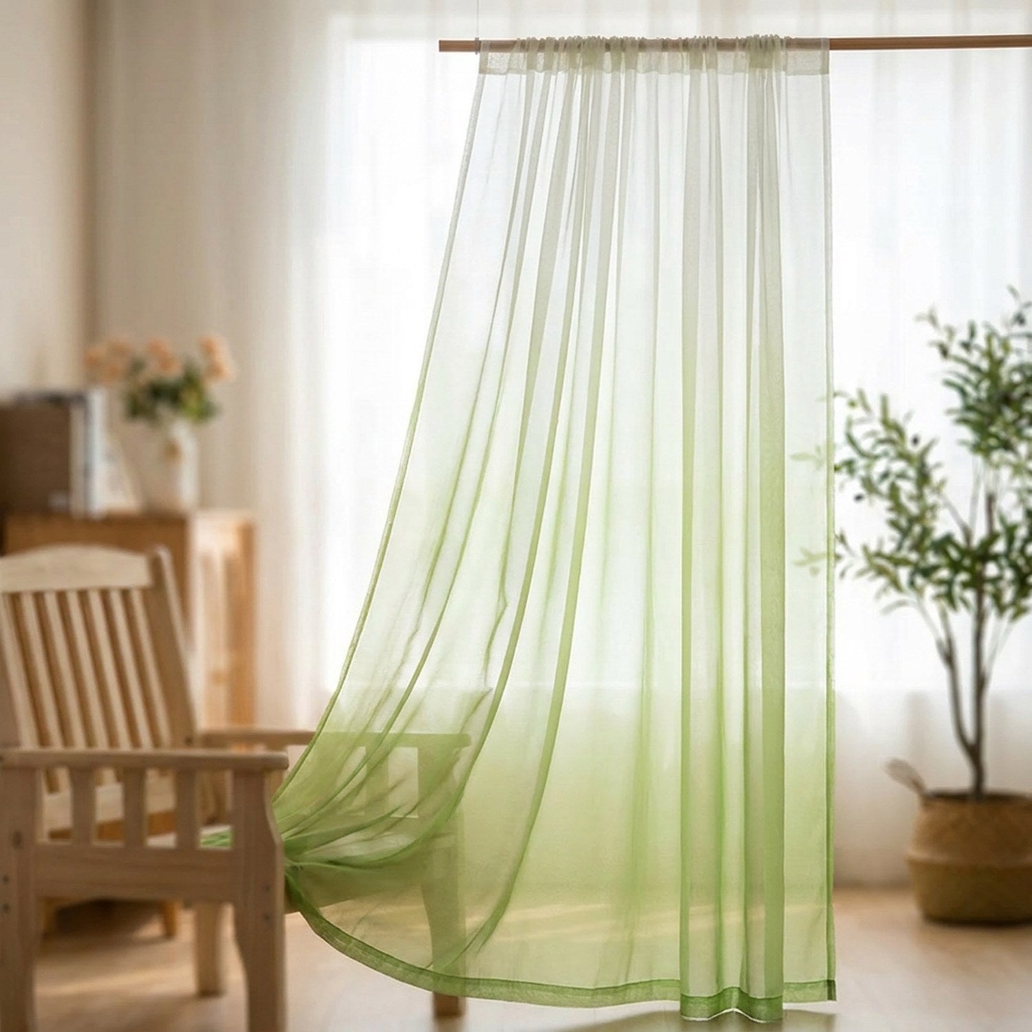 Voilage tulle dégradé vert suspendu à une tringle devant une fenêtre lumineuse