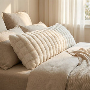 Traversin en peluche blanche posé sur un lit dans une chambre lumineuse et cocooning