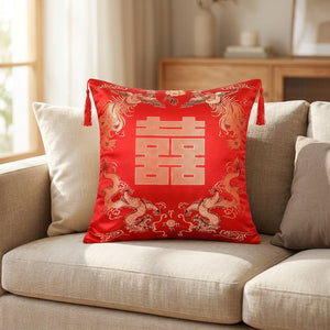 Housse de coussin en satin brodé rouge et or posée sur un canapé beige avec motifs chinois dorés