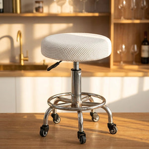 Housse de chaise ronde blanche extensible posée sur un tabouret de bar dans un intérieur chaleureux