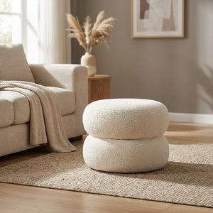 Pouf rond en laine bouclée blanche posé dans un salon lumineux et épuré
