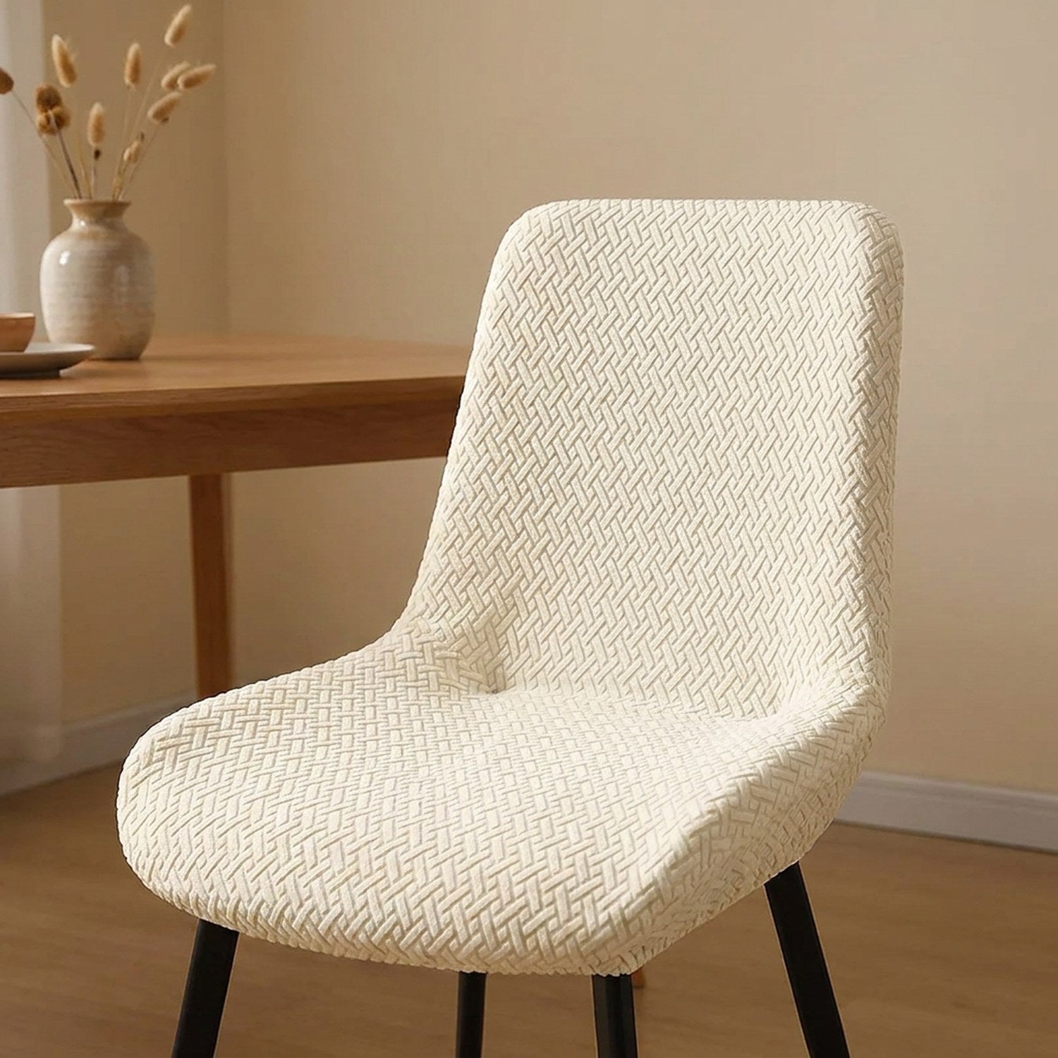 Housse de chaise jacquard ivoire installée sur une chaise dans une salle à manger chaleureuse