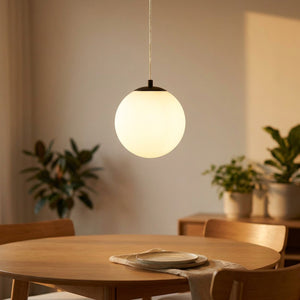 Suspension boule en verre opalin noire allumée au-dessus d une table à manger en bois