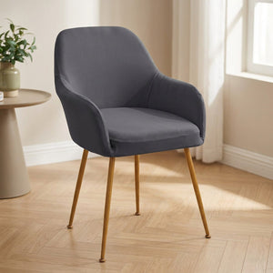 Housse de fauteuil extensible gris foncé installée sur une chaise à accoudoirs dans une salle à manger lumineuse