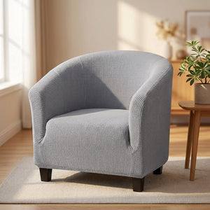 Housse de fauteuil cabriolet en maille polaire grise installée sur un fauteuil club dans un salon chaleureux