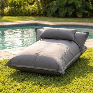 Pouf flottant gris imperméable posé sur une pelouse au bord d'une piscine