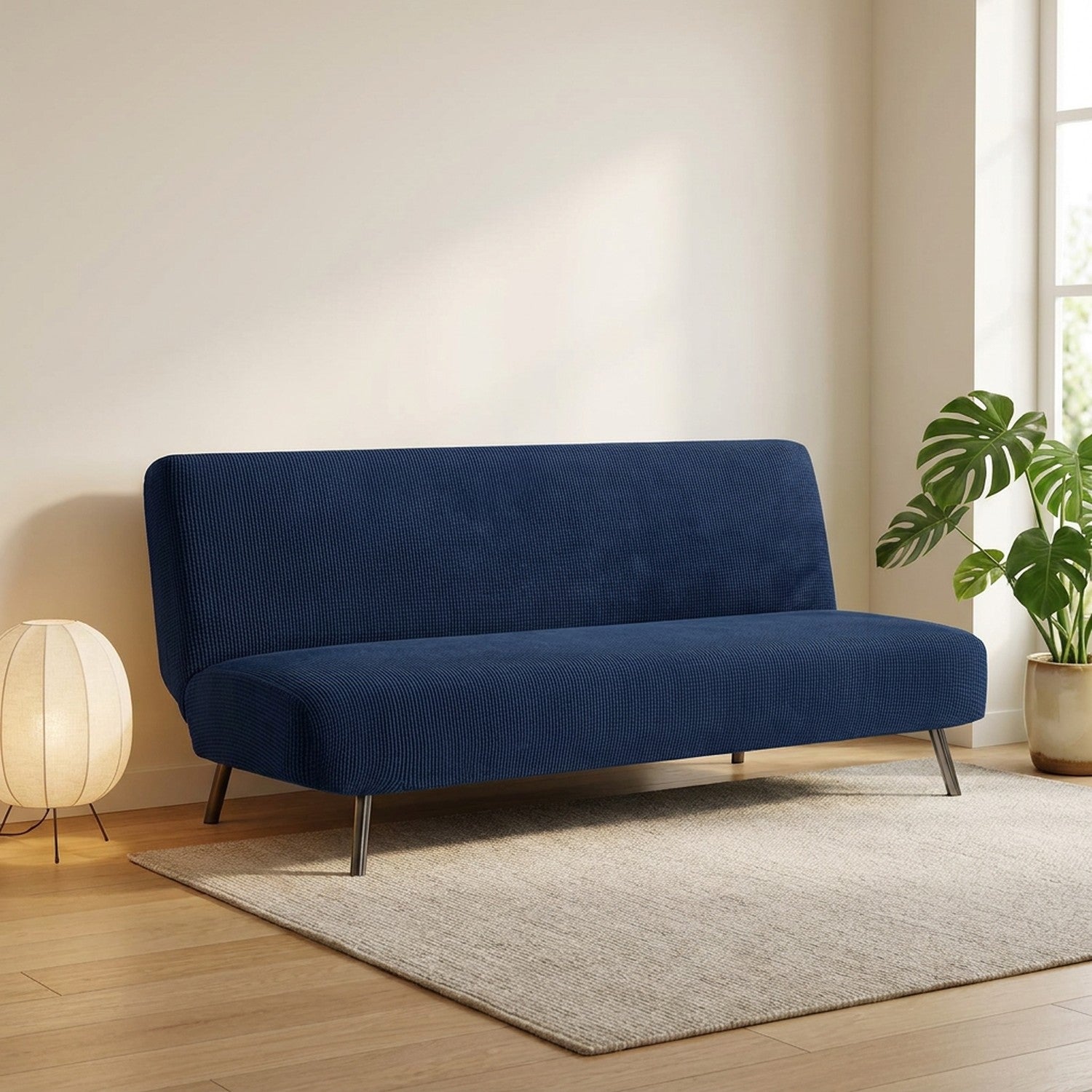 Housse de canapé convertible bleu marine posée sur une banquette sans accoudoirs dans un salon lumineux