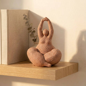 Statuette de femme en résine à la texture sableuse posée sur une étagère dans un intérieur chaleureux
