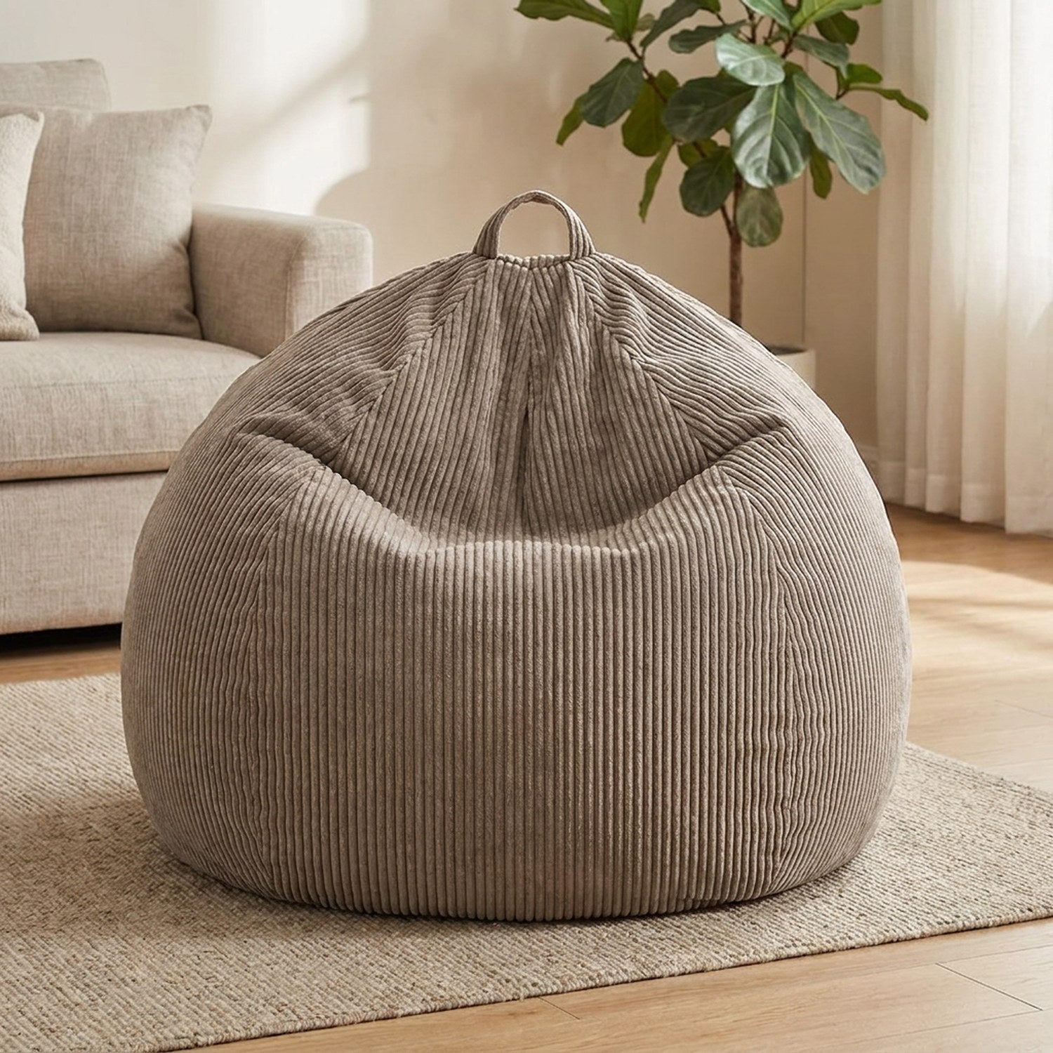 Housse de pouf poire en velours côtelé taupe posée dans un salon lumineux avec plaid et coussins