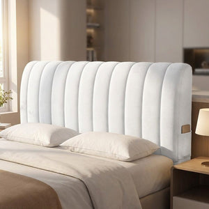 Housse de tête de lit capitonnée en velours blanc installée sur un lit dans une chambre chaleureuse