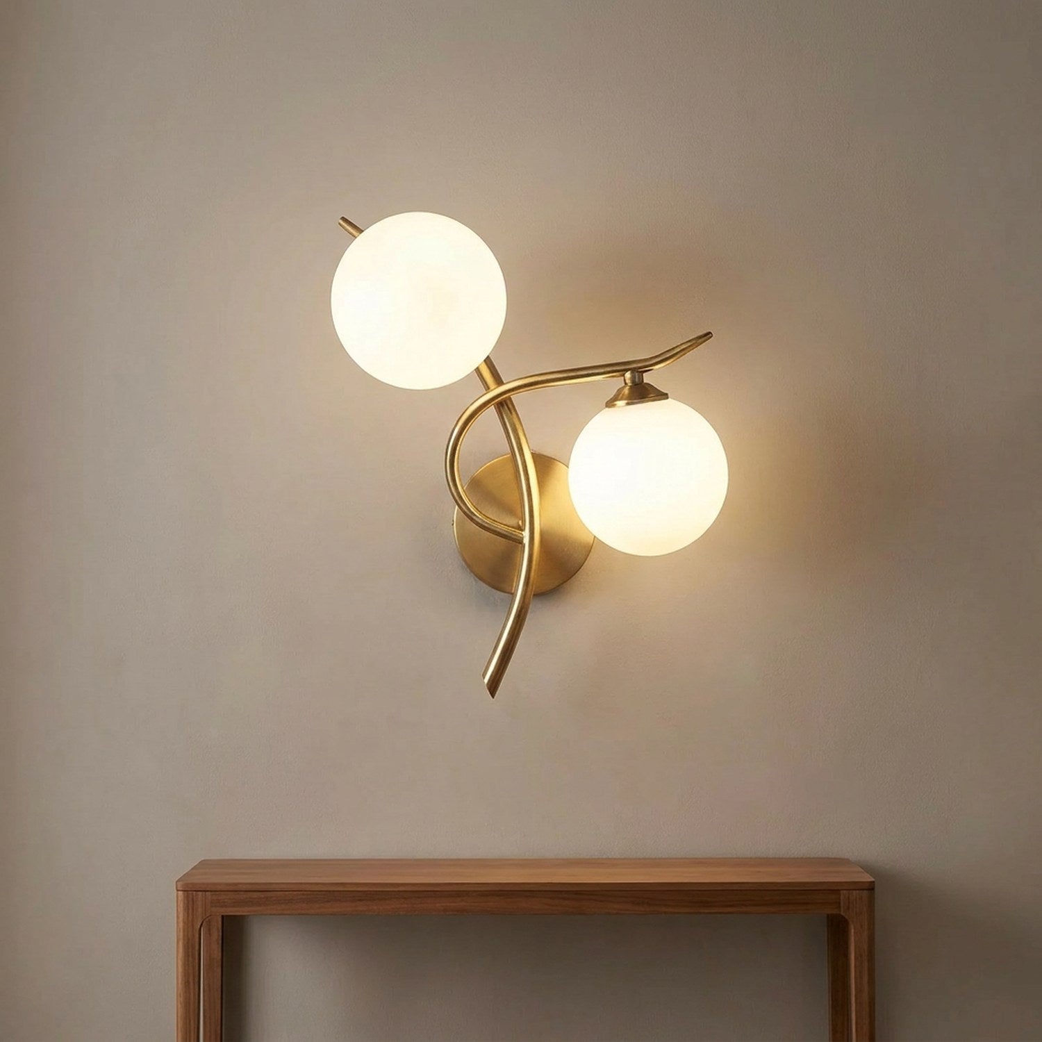 Applique murale dorée à deux boules de verre dépoli allumée au-dessus d'une console en bois