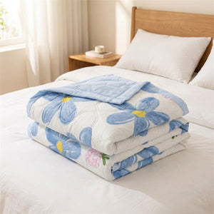 Couvre-lit matelassé d'été motif grandes marguerites bleues plié sur un lit