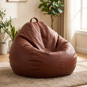 Pouf poire en simili cuir marron posé au sol dans un intérieur cosy