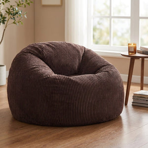 Pouf marron en velours côtelé posé au sol près d'une fenêtre