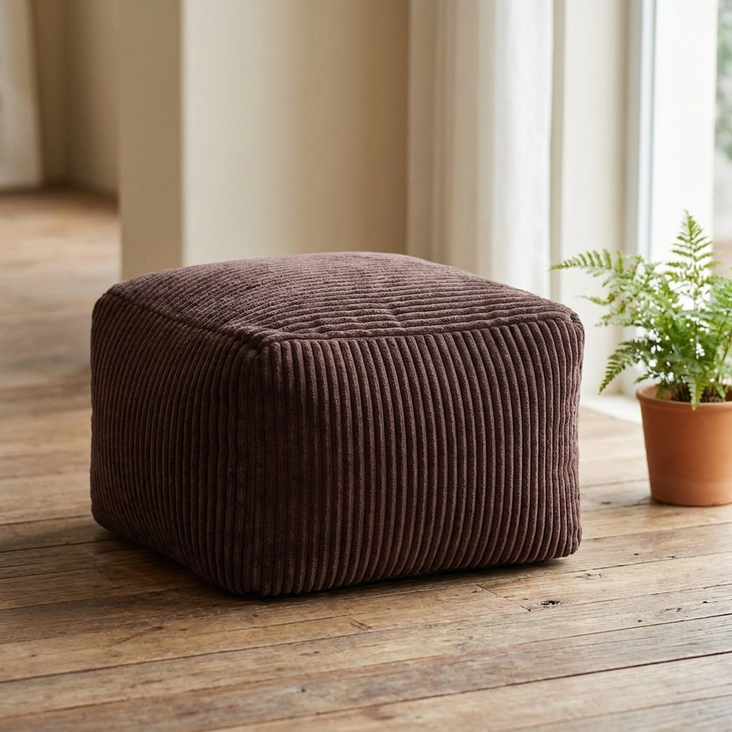 Tabouret pouf marron en velours côtelé posé au sol