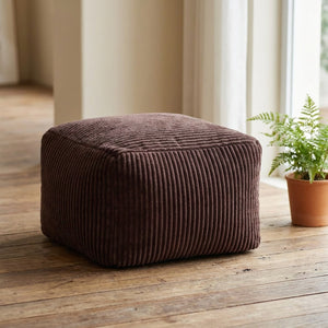 Tabouret pouf marron en velours côtelé posé au sol