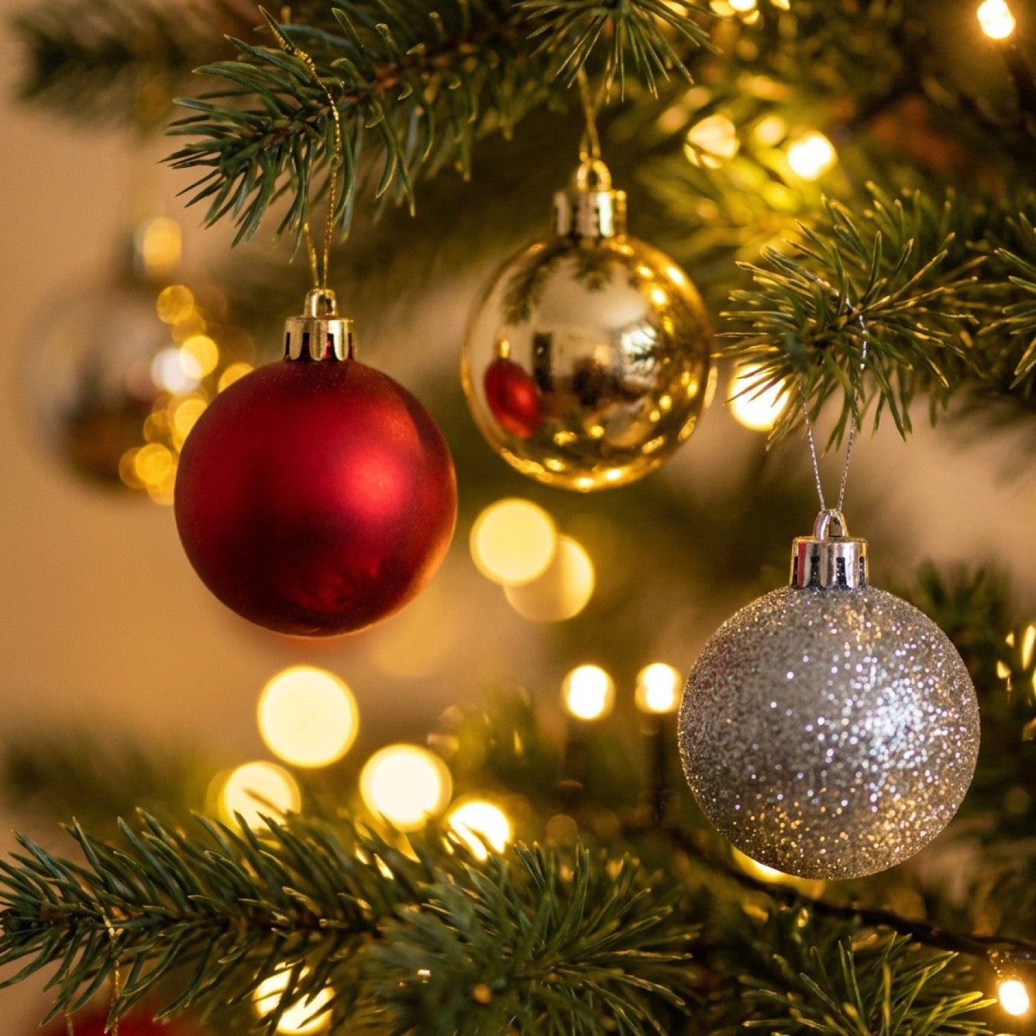 Mini boules de Noël finitions assorties accrochées sur branche avec lumières