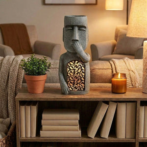 Statue moaï cache bouche sur étagère avec livres plante et bougie déco intérieure