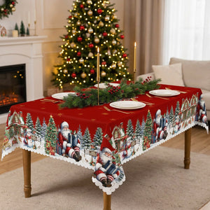 Nappe de Noël rectangulaire rouge à bord festonné sur une longue table dressée avec assiettes blanches bougies dorées et sapin illuminé
