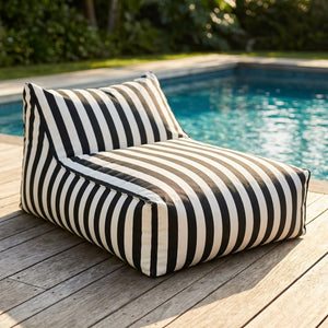 Housse de pouf géant flottant à rayures noires et blanches posée au bord d'une piscine