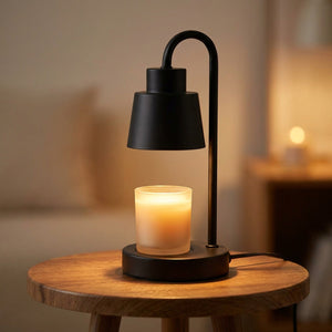 Lampe chauffe-bougie noire allumée sur une petite table ronde en bois