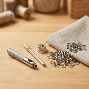 Kit de pose d'œillets en métal avec perforateur matrice et œillets argentés sur une table