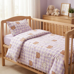 Parure de lit bébé motif ourson en coton lavande posée sur un berceau