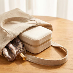Boîte à bijoux en velours posée sur une table en bois avec sac en lin et foulard à motifs