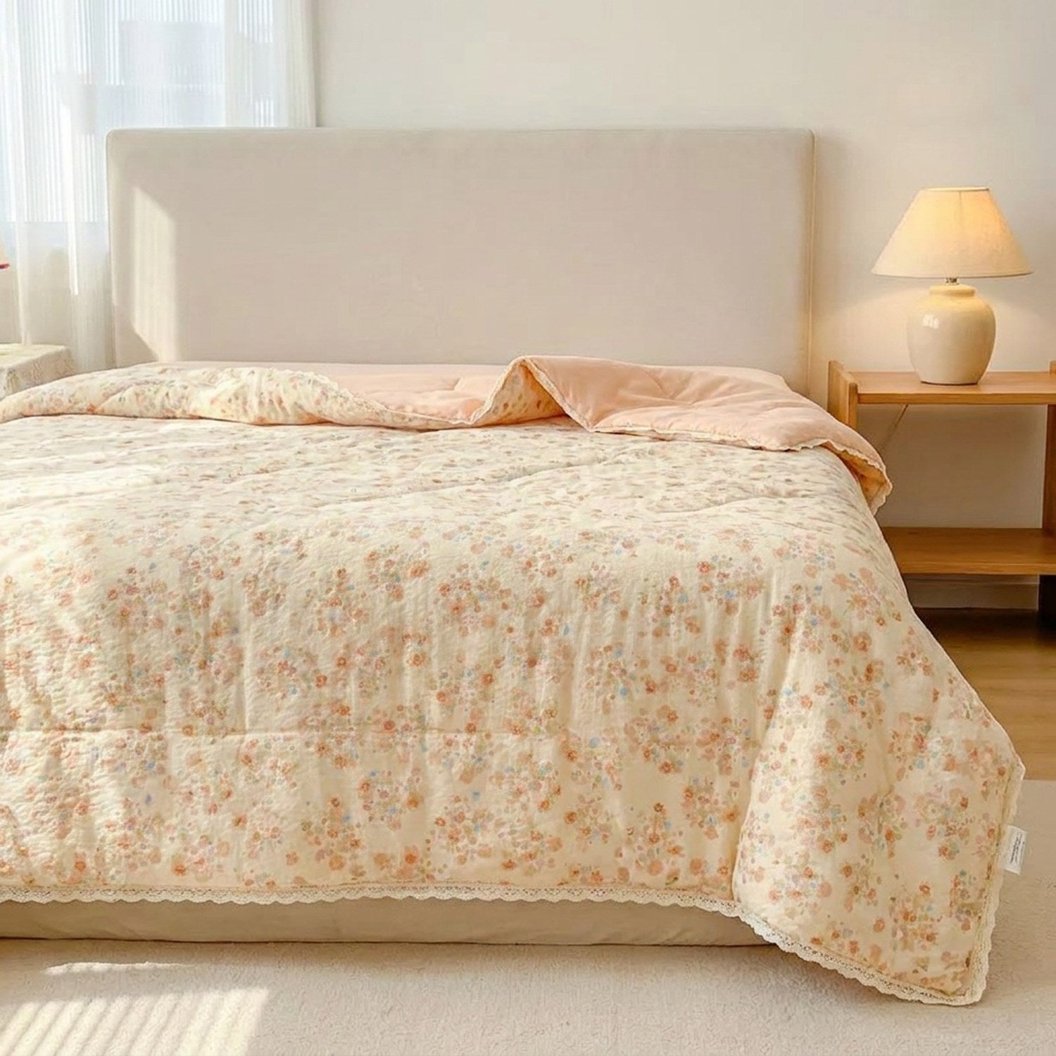 Couette d'été fleurie rose étalée sur un lit avec lampe de chevet