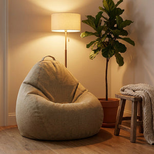 Pouf poire beige dans un coin cocooning avec lampadaire et plante verte