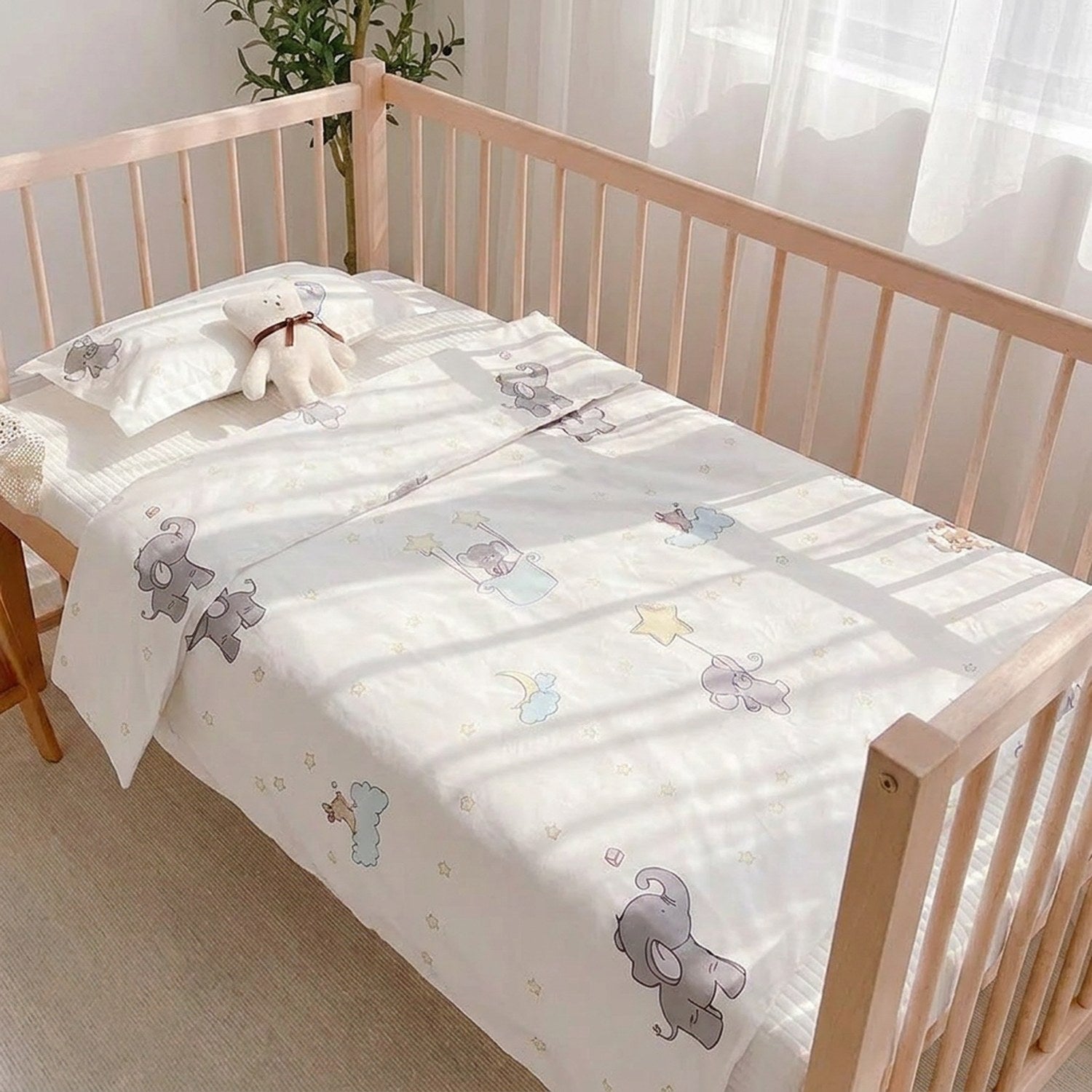 Parure de lit bébé sur un berceau en bois dans une chambre lumineuse avec peluche