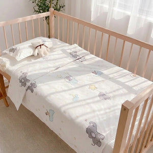 Parure de lit bébé sur un berceau en bois dans une chambre lumineuse avec peluche