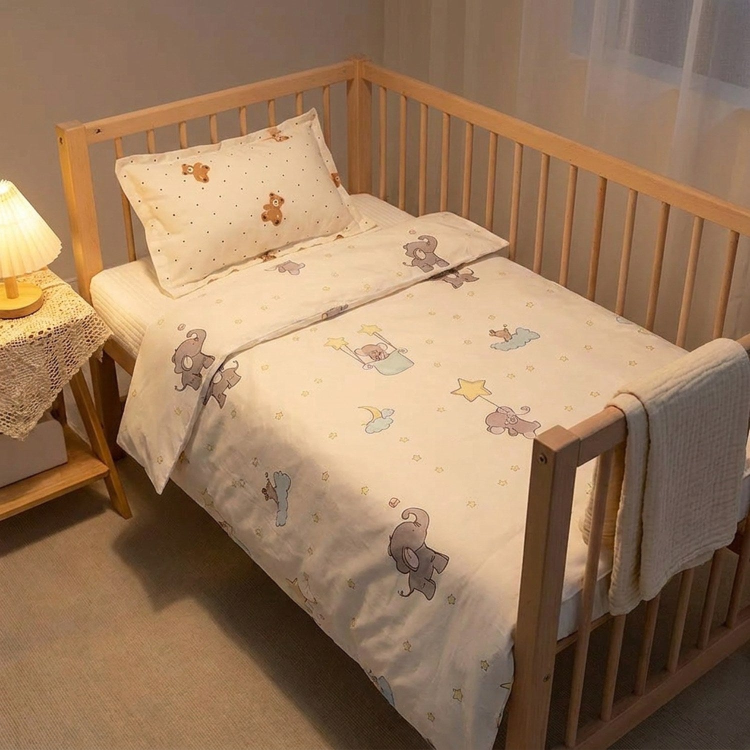 Parure de lit bébé sur un berceau avec table de chevet et lampe chaleureuse