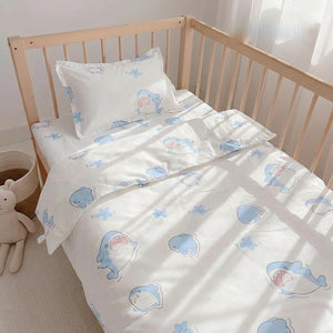 Parure de lit bébé motif requins bleus installée sur un berceau