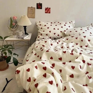 Parure de lit cœur rouge froissée sur un lit avec plante verte à côté